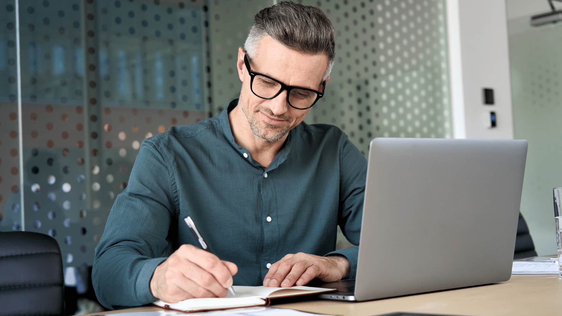 man writing down notes while working 