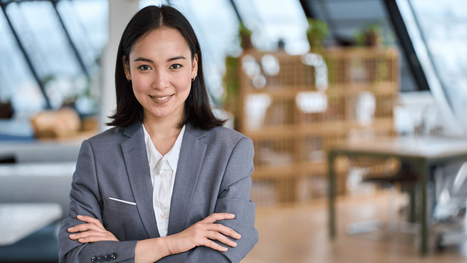 woman crossing arms while smiling and staring at camera 