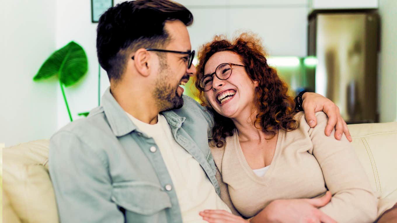 Woman showering partner in words of positivity as they laugh together on couch. 