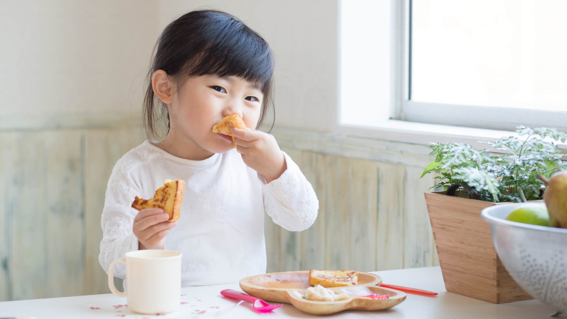 Little girl eating breakfast at a table