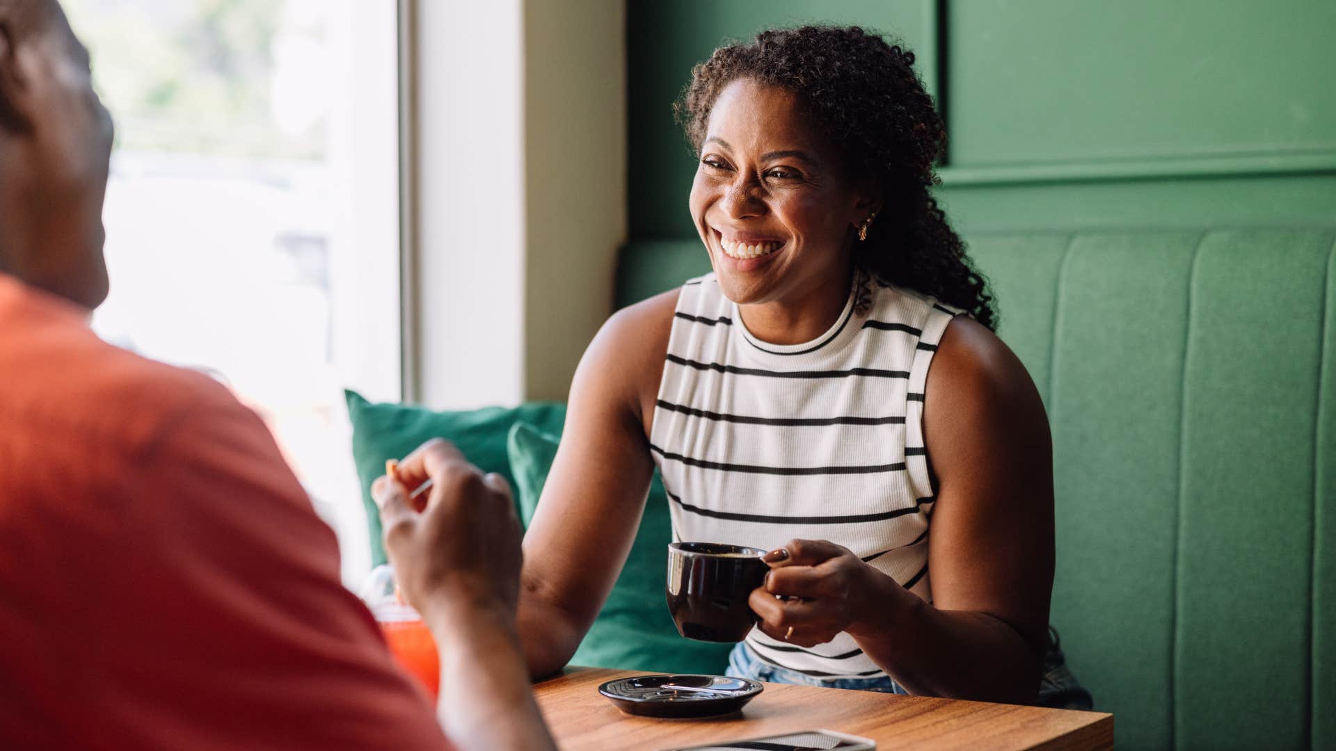 Woman smiling while drinking coffee in a coffee shop.