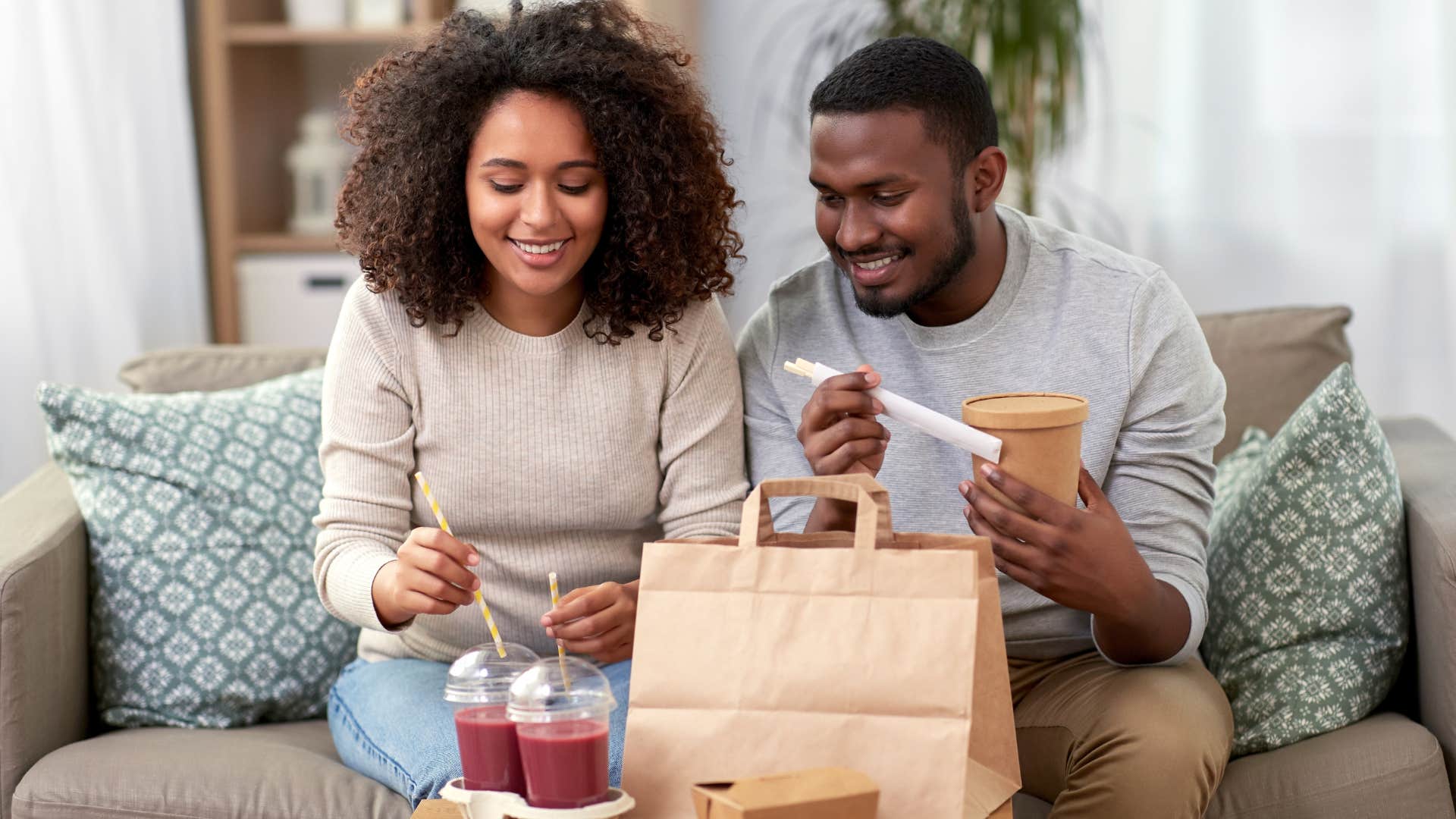 Couple eating fast food together on the couch.