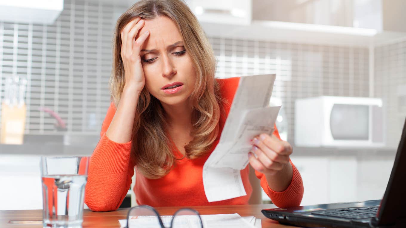 Woman looking stressed doing bills on her laptop.