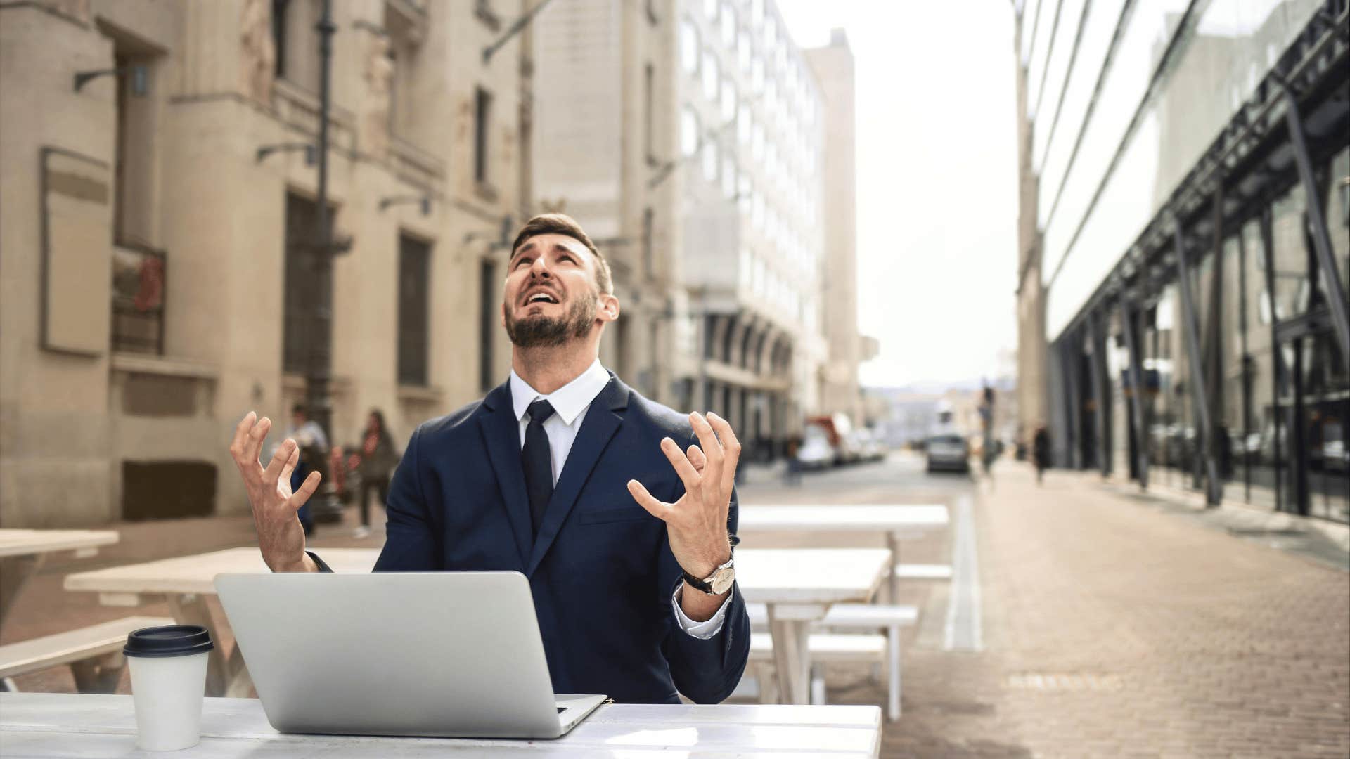 man throwing his hands up in frustration with a laptop