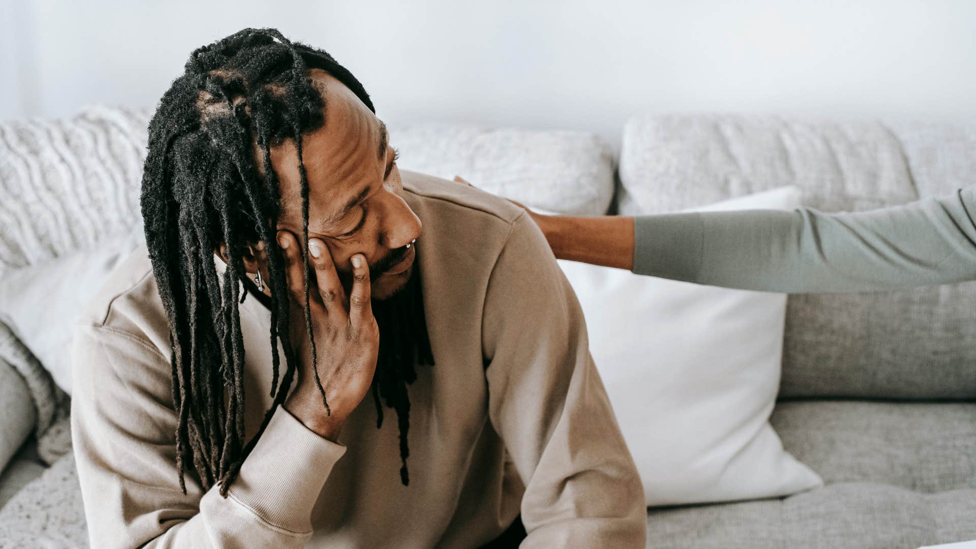 someone comforting man with his head in his hand