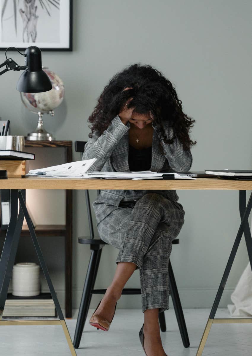 frustrated worker with head in her hands at her desk