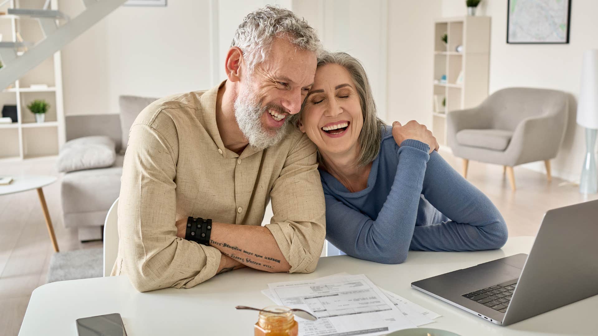 Gen X couple smiling on their laptop together.