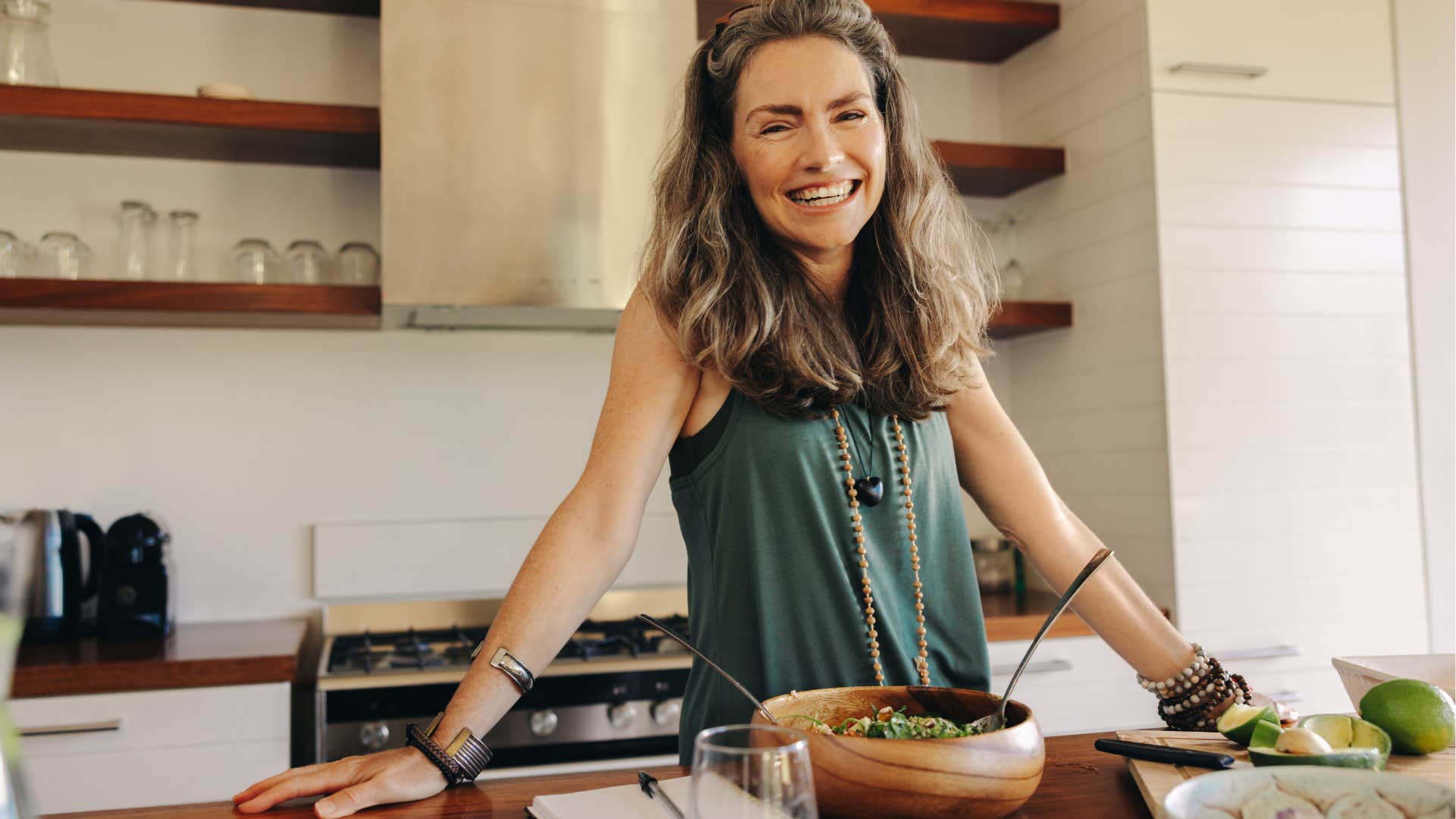 Gen X woman smiling with food in her kitchen.