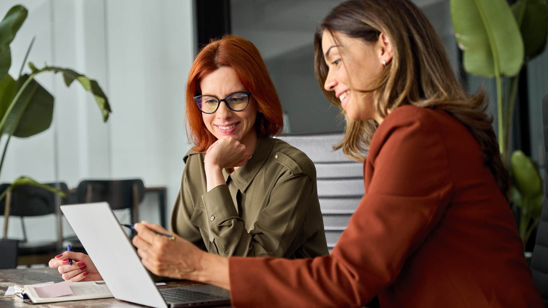 Two women smiling and looking at a laptop together.