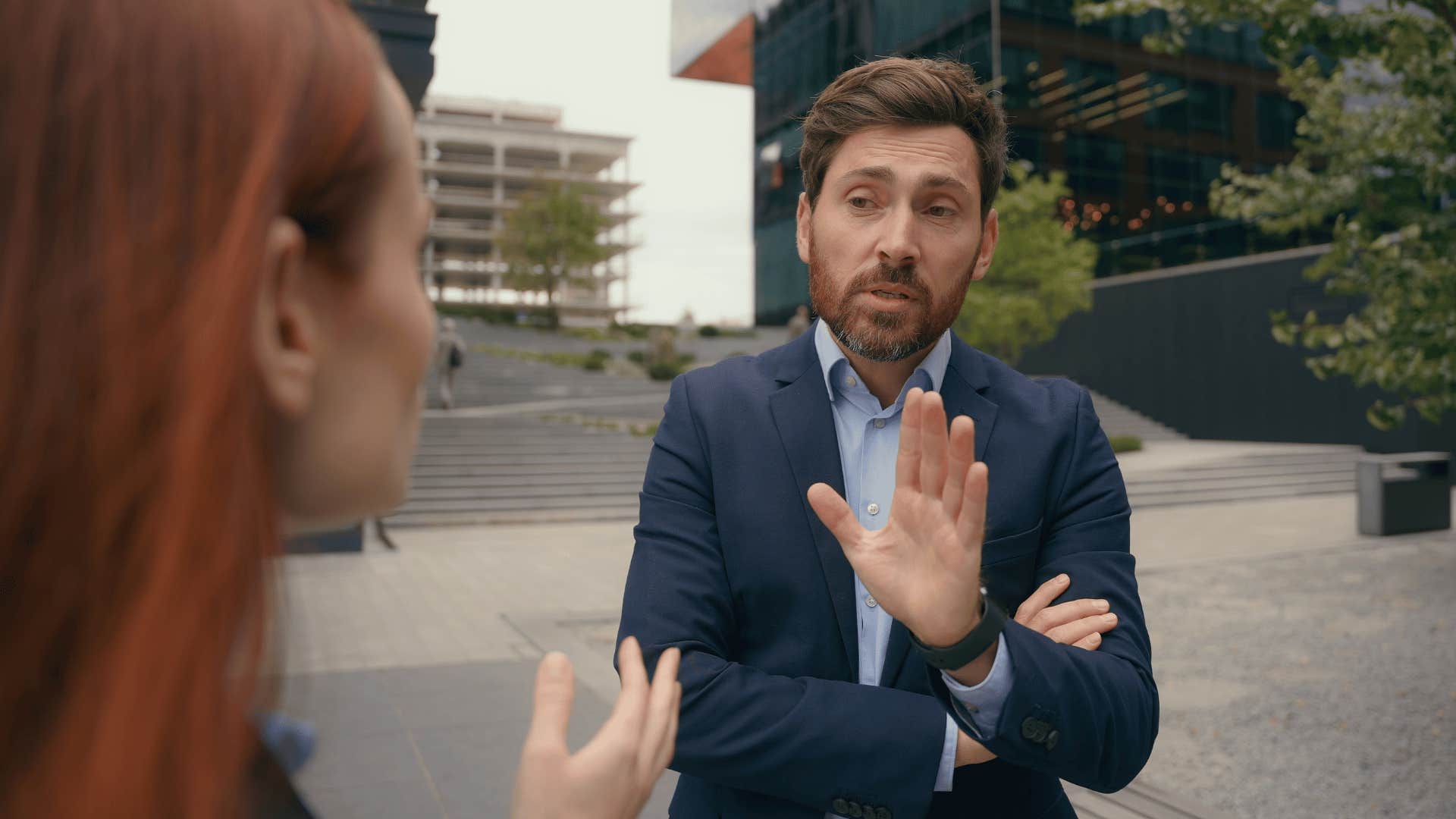 man holding up hand while woman talks 