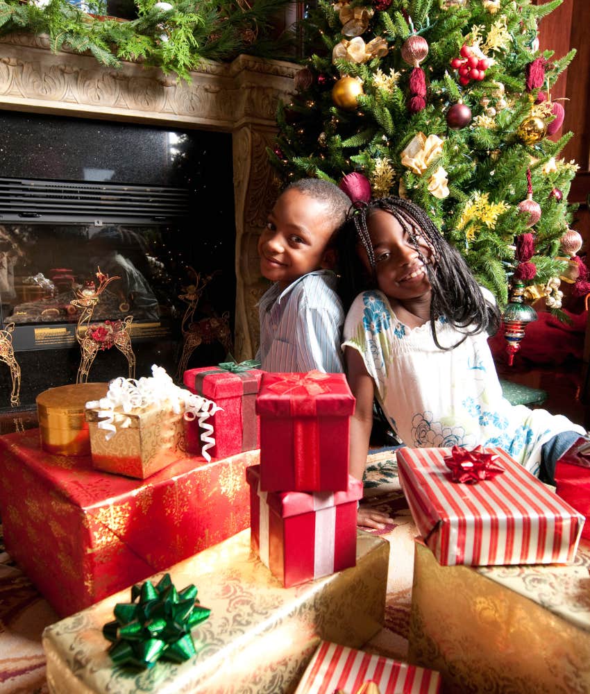 two kids sitting amid a pile of holiday presents