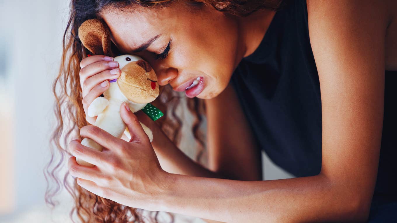 Grieving woman, holding on to babies toy. 