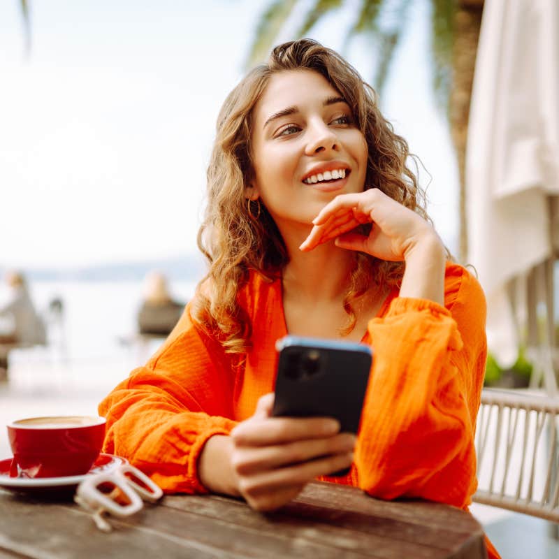 portrait of young woman reading text message on mobile phone at coffee shop.