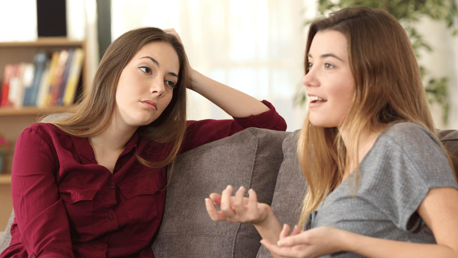 woman talking on the couch while the other gives her an annoyed look