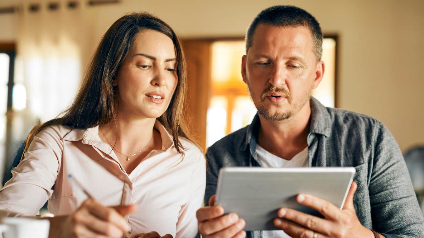 husband and wife looking at bank statement after depositing her work bonus