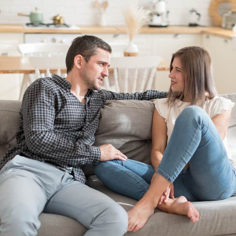 couple having conversation while resting on sofa at home