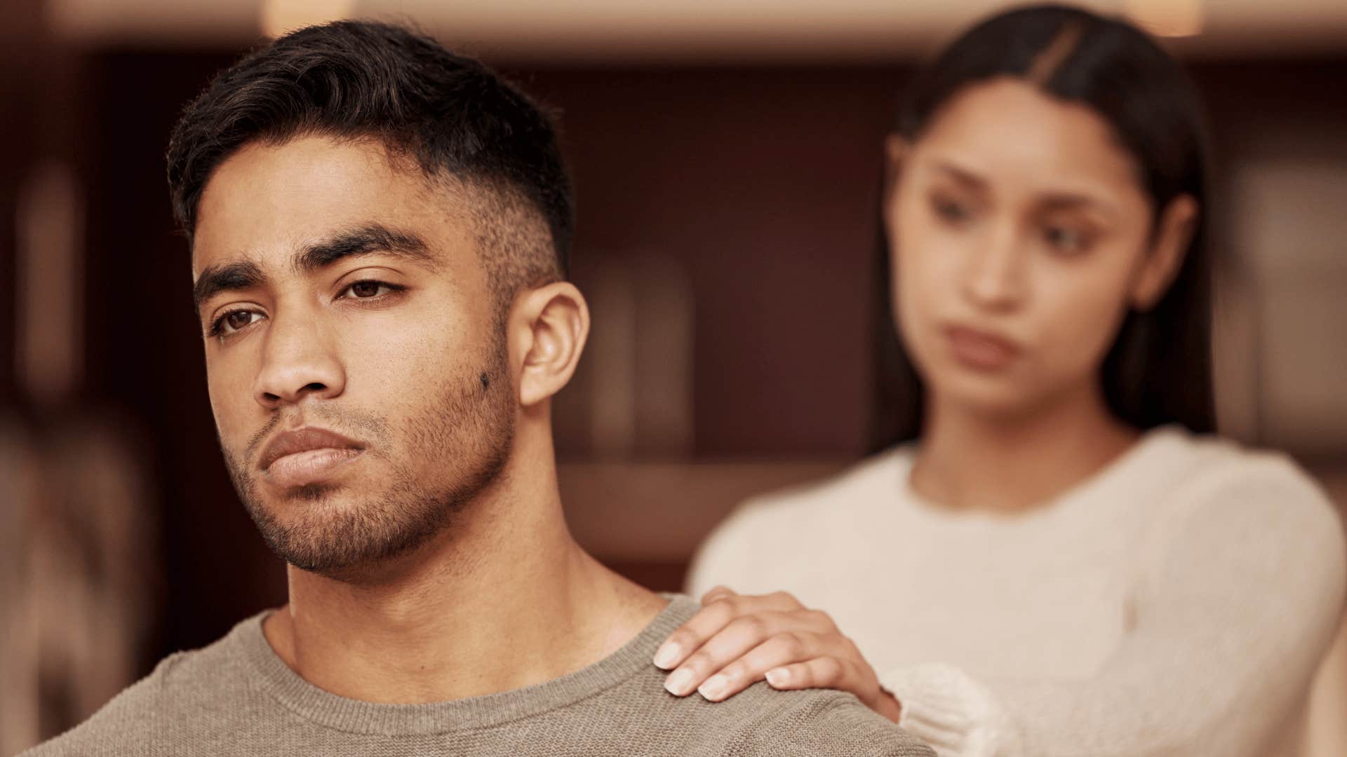 Wife touches shoulder of burdened husband