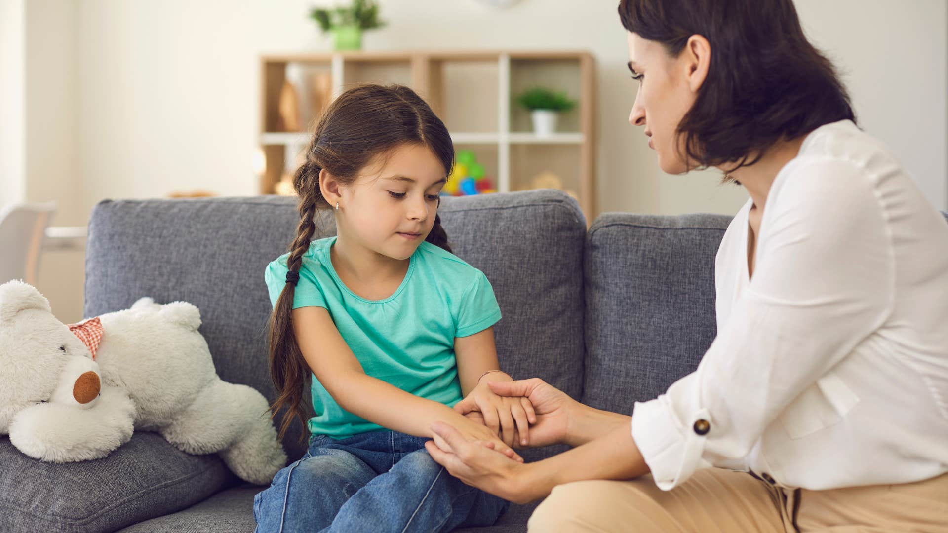 Mom holding her daughter's hands and smiling.