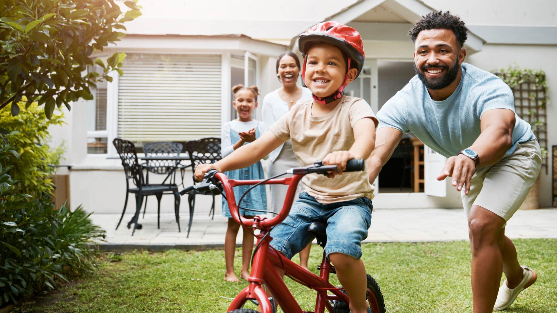 Dad pushing his young son on a bicycle.