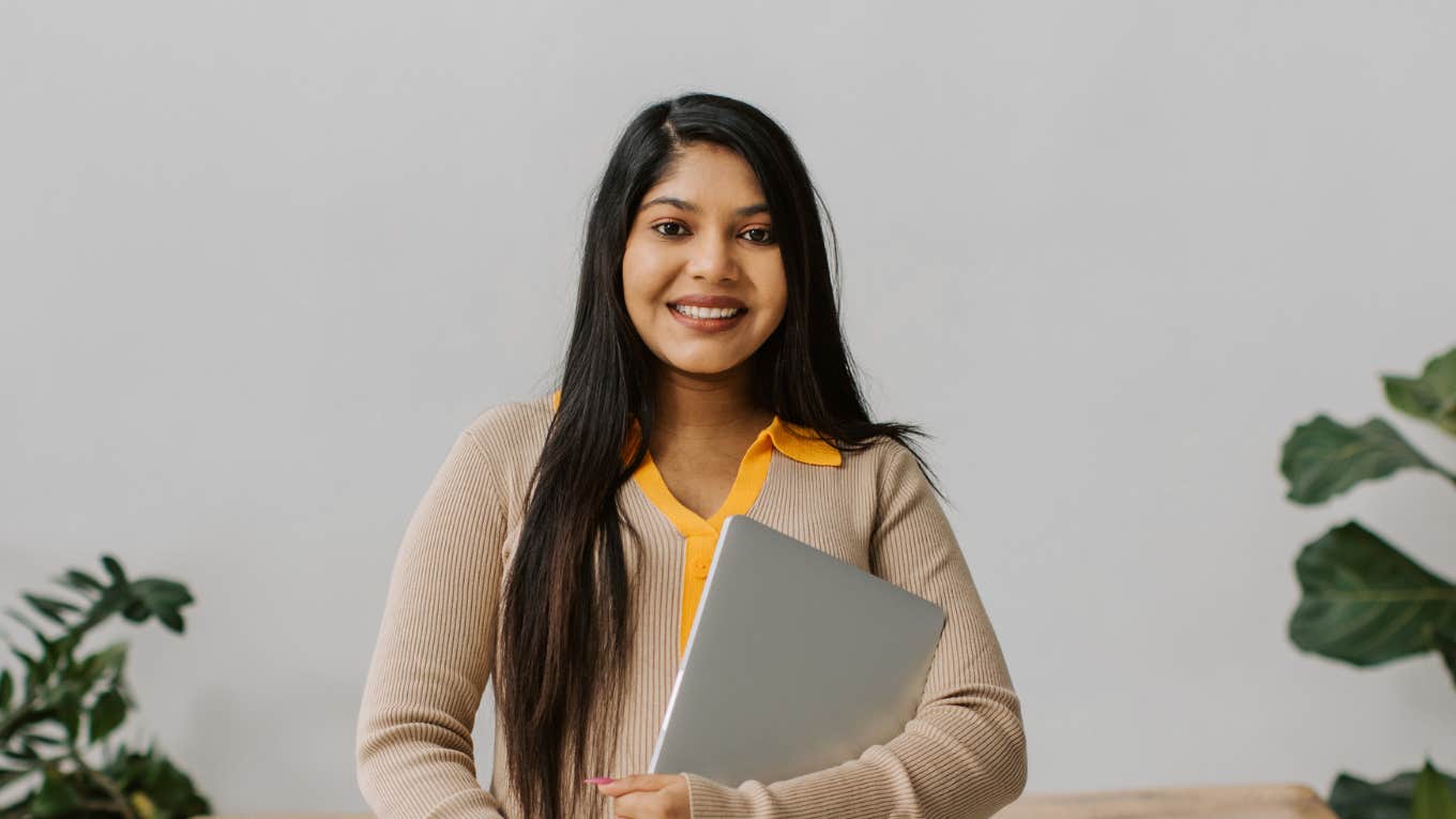 professional woman smiling while holding laptop