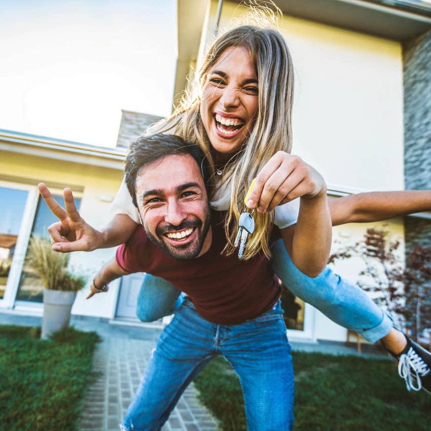 Happy young couple holding home keys after buying real estate