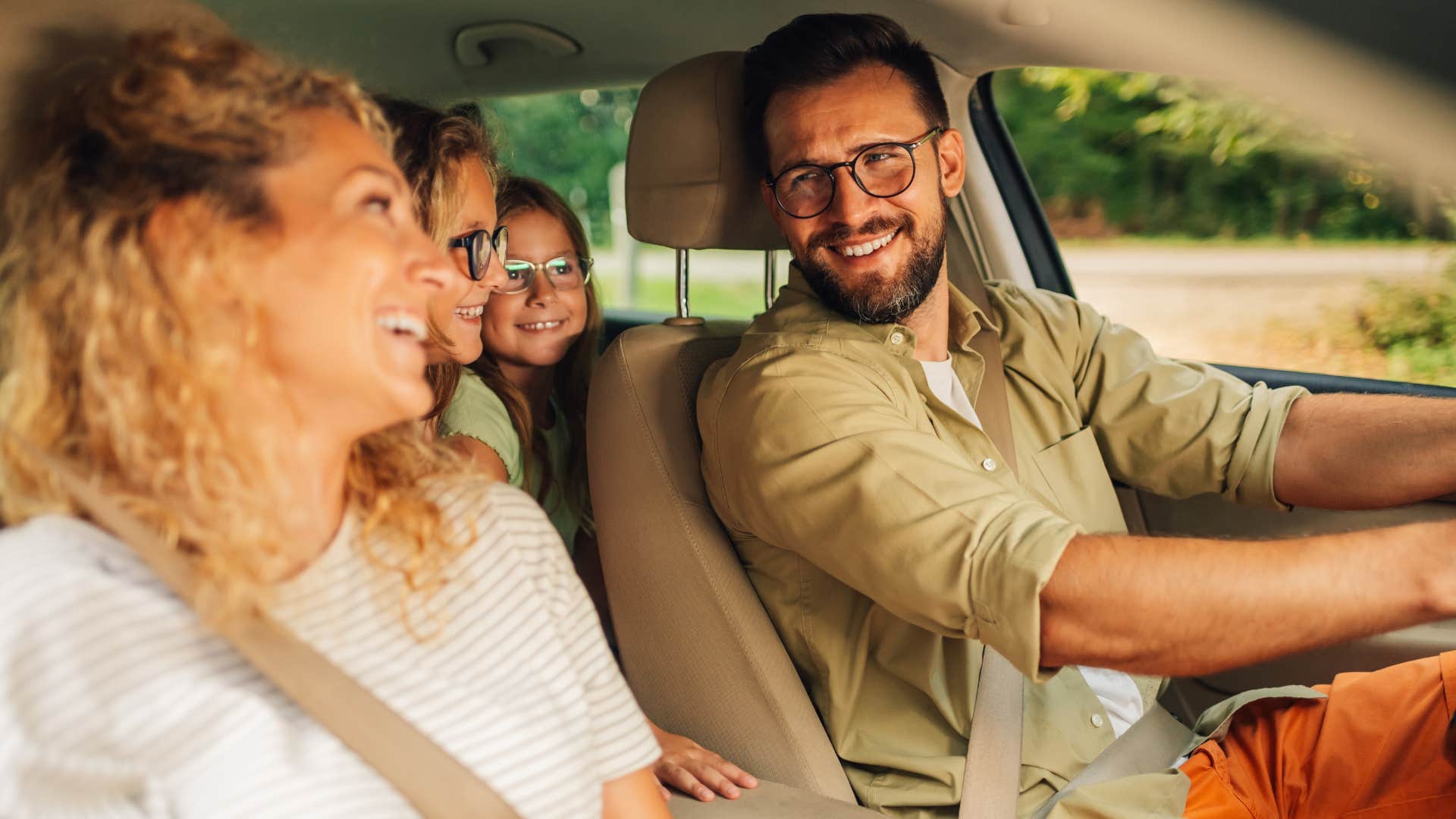 Family smiling in a car on a road trip