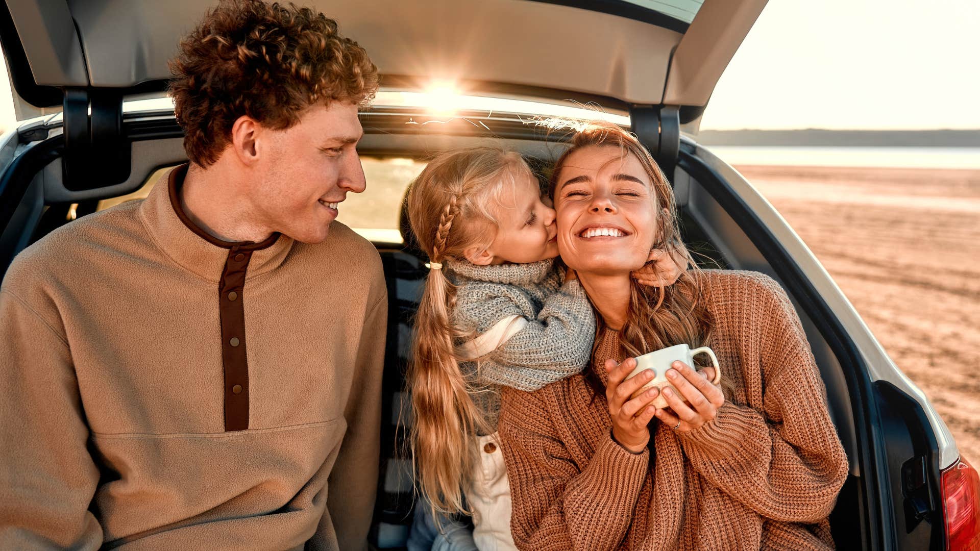 Family smiling outside of their car