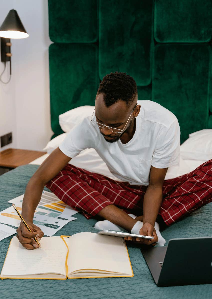 man sitting in bed and journaling