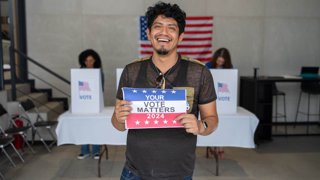 smiling man holding a Your Vote Matters 2024 sign at a US election polling station