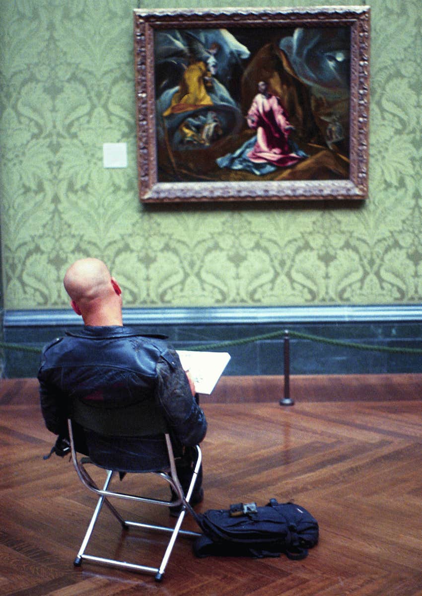 man studying a painting in a museum