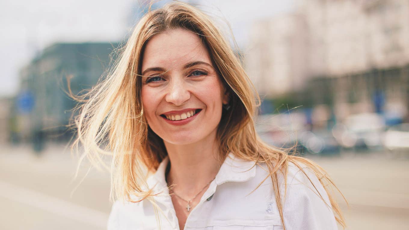 smiling thoughtful woman standing outside