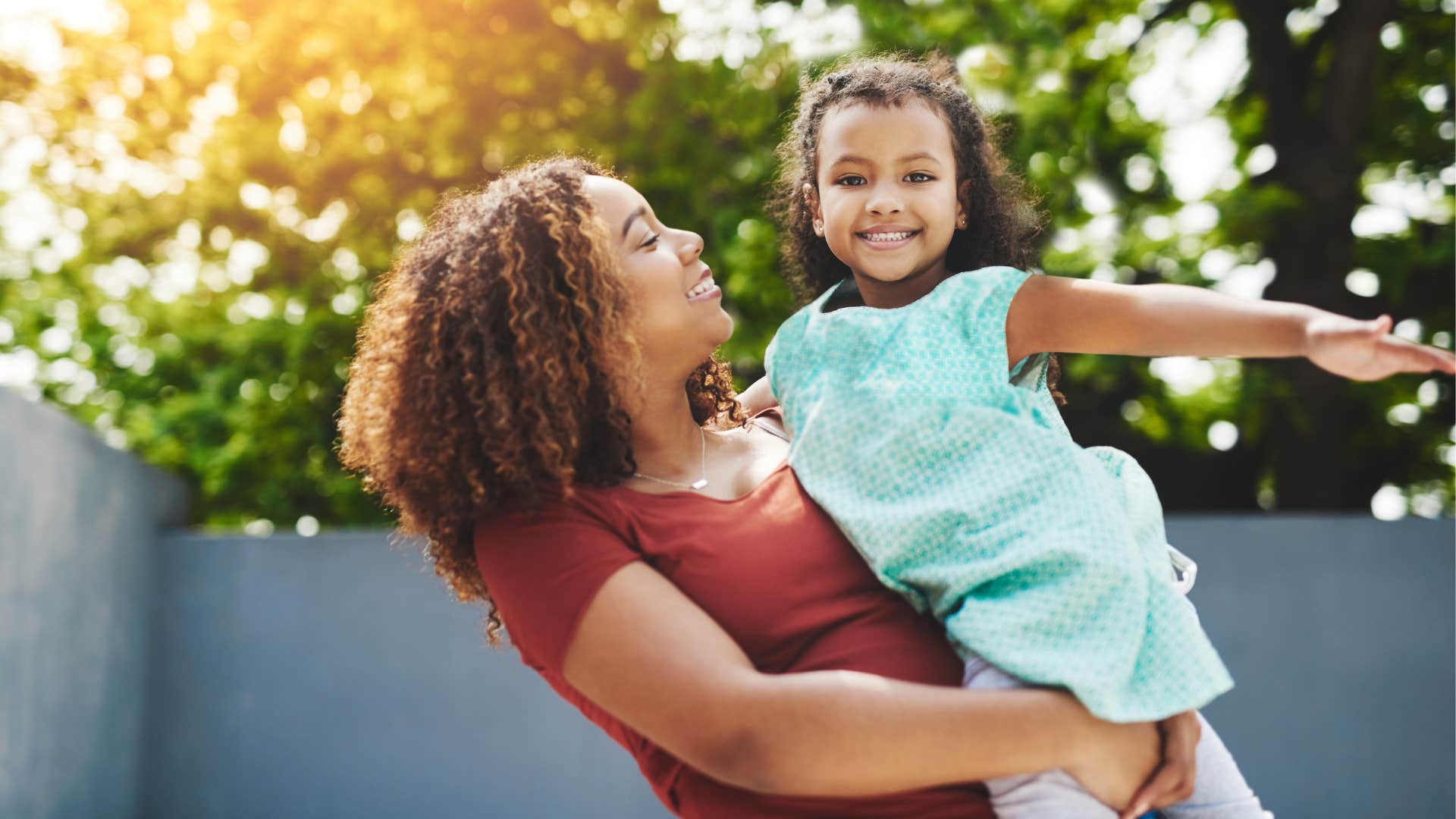 Mom holding her young daughter and smiling.