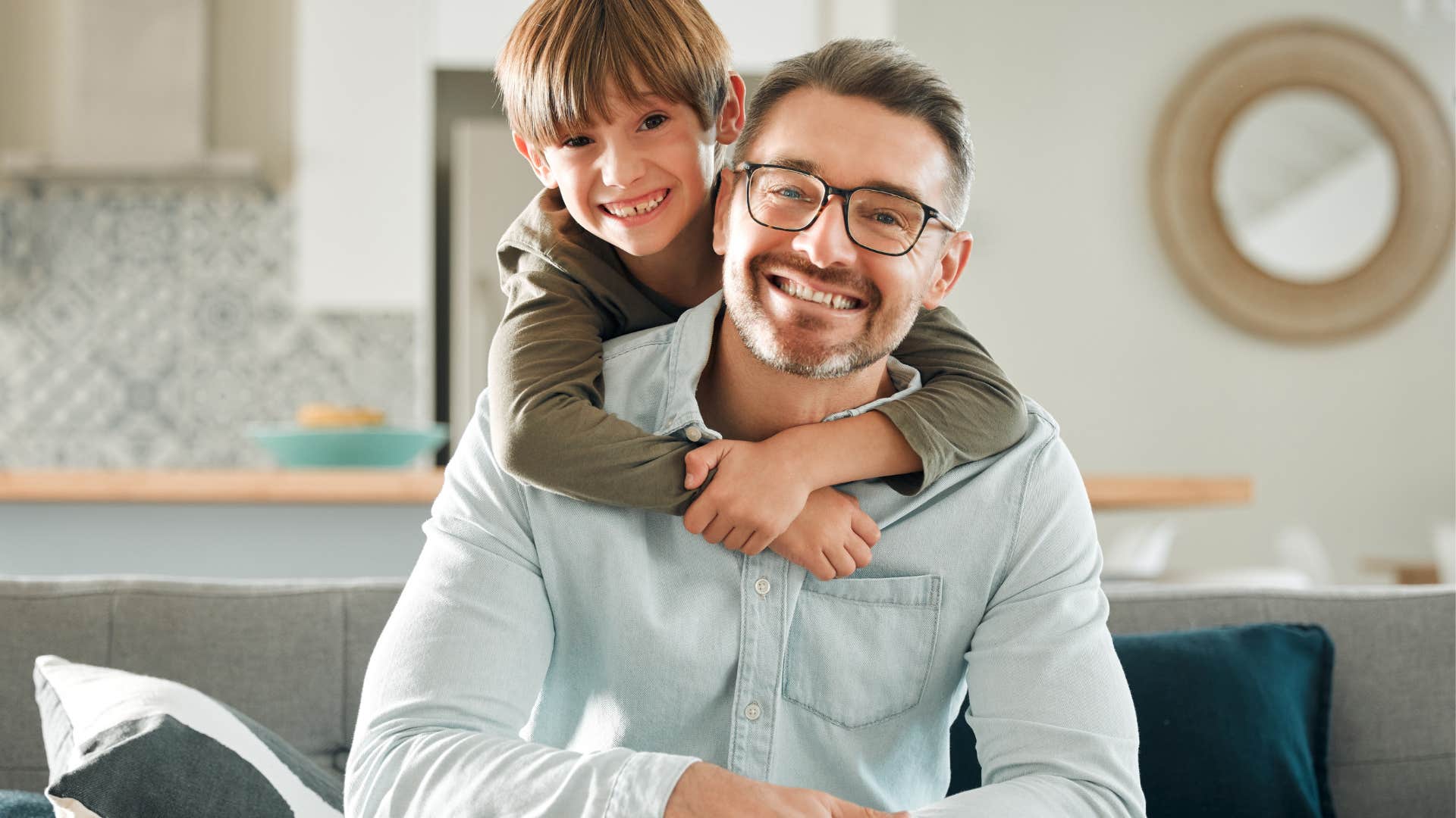 Young boy hugging his dad while smiling.