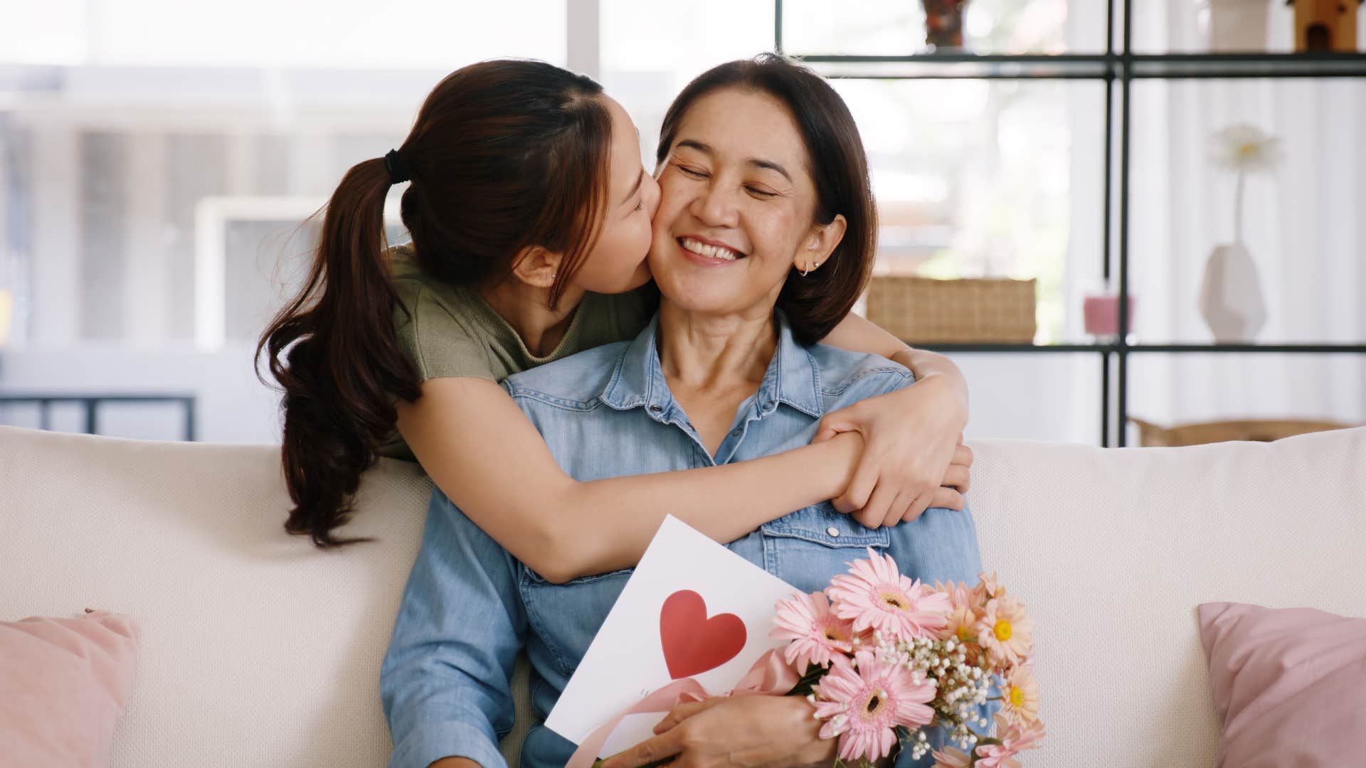 Young daughter smiling and hugging her mother.