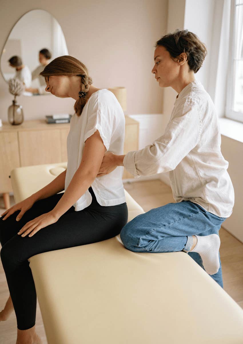 massage therapist helping woman with back pain