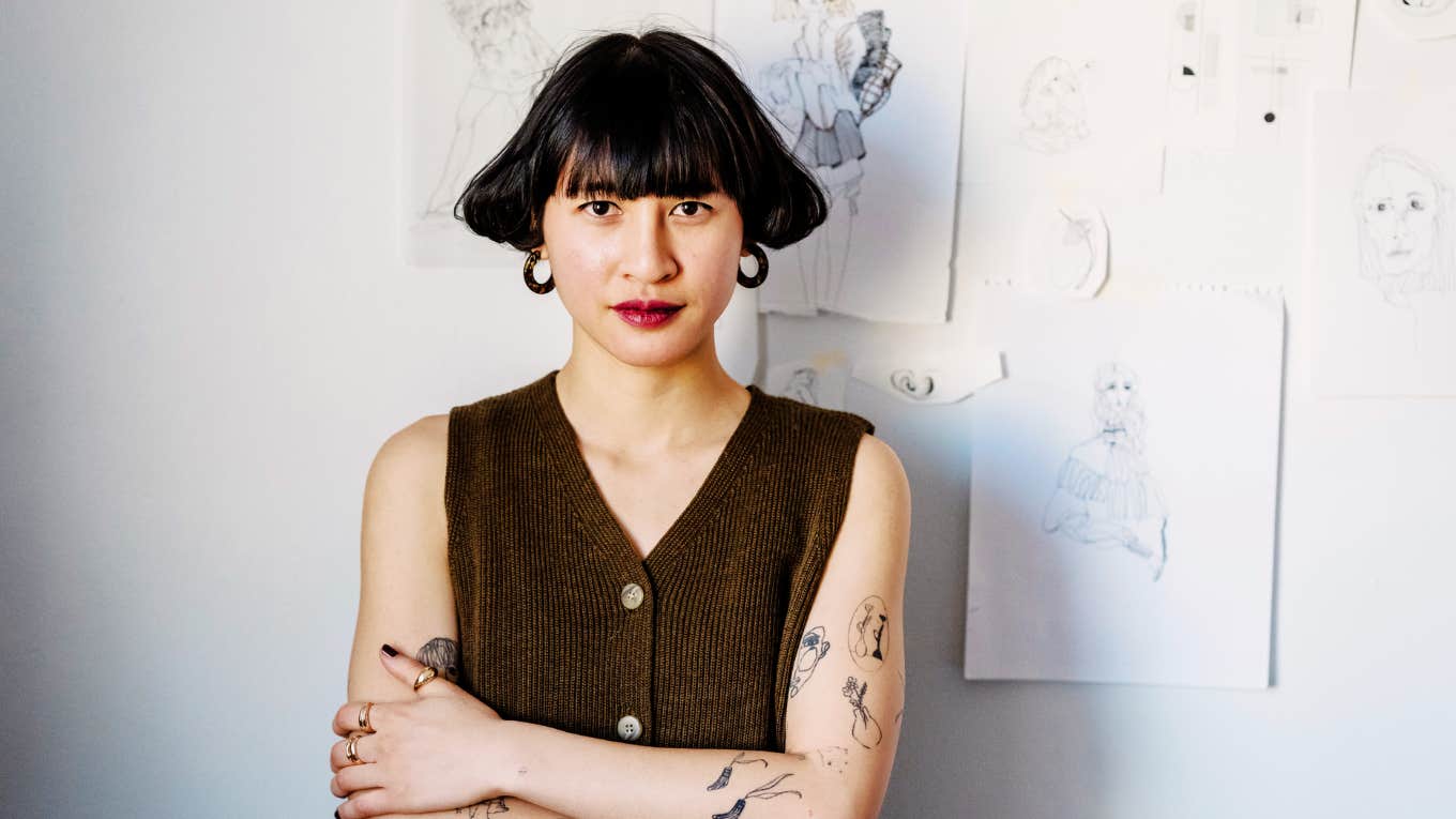 Woman artist in front of her sketches.