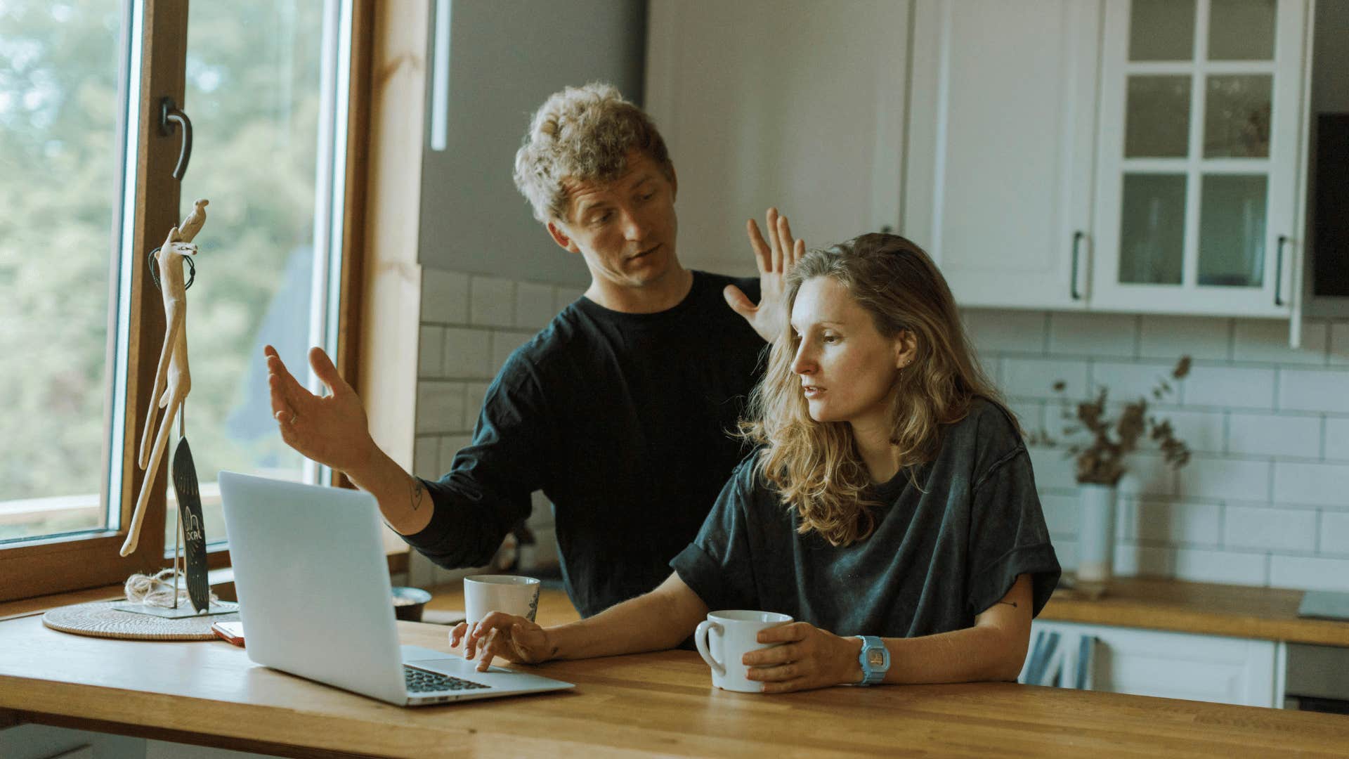 woman on laptop while man talks to her