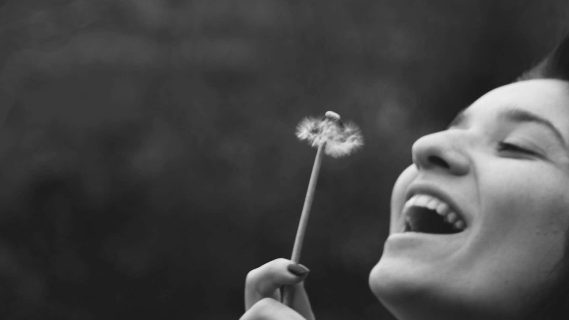 woman smiling holding a dandelion