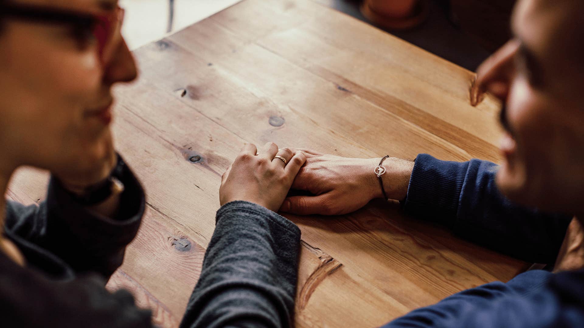 couple sitting at a table holding hands and looking at each other