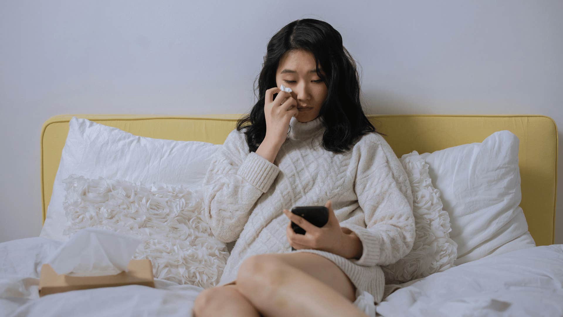 woman crying in bed with phone