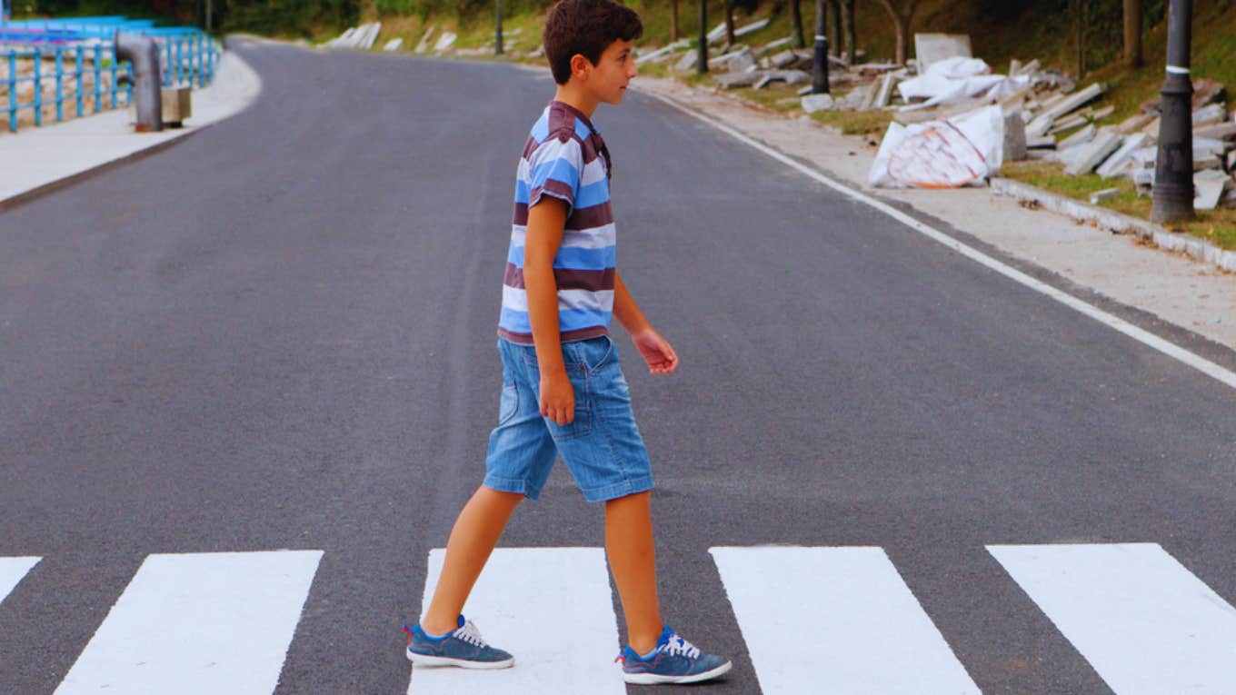 young boy walking alone on road 