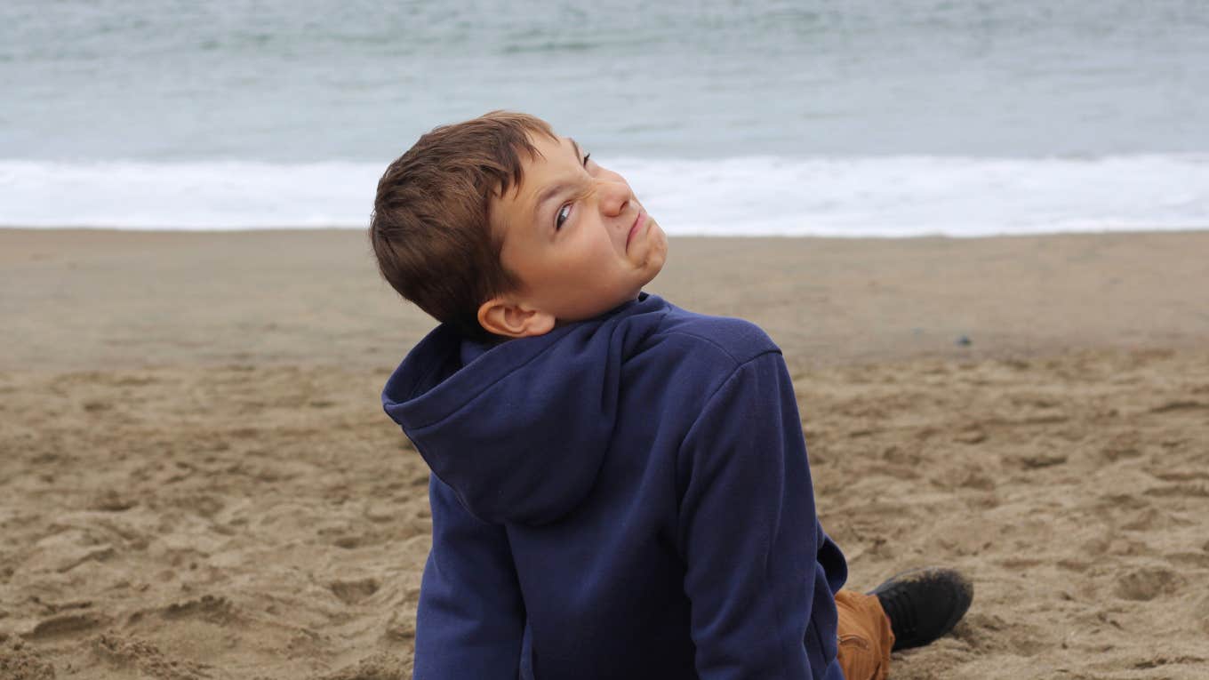 young boy making a face while sitting on the beach