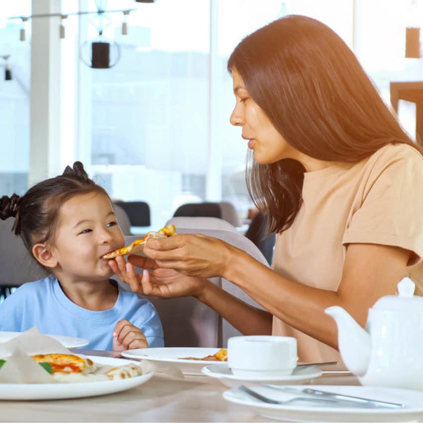 mom feeding toddler at restaurant 