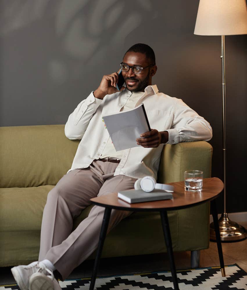 man sitting on couch talking on phone