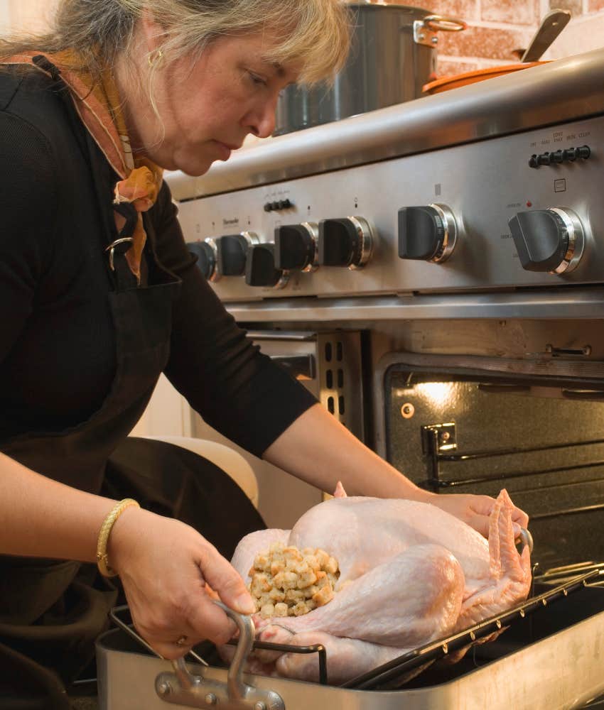 woman putting Thanksgiving turkey in oven