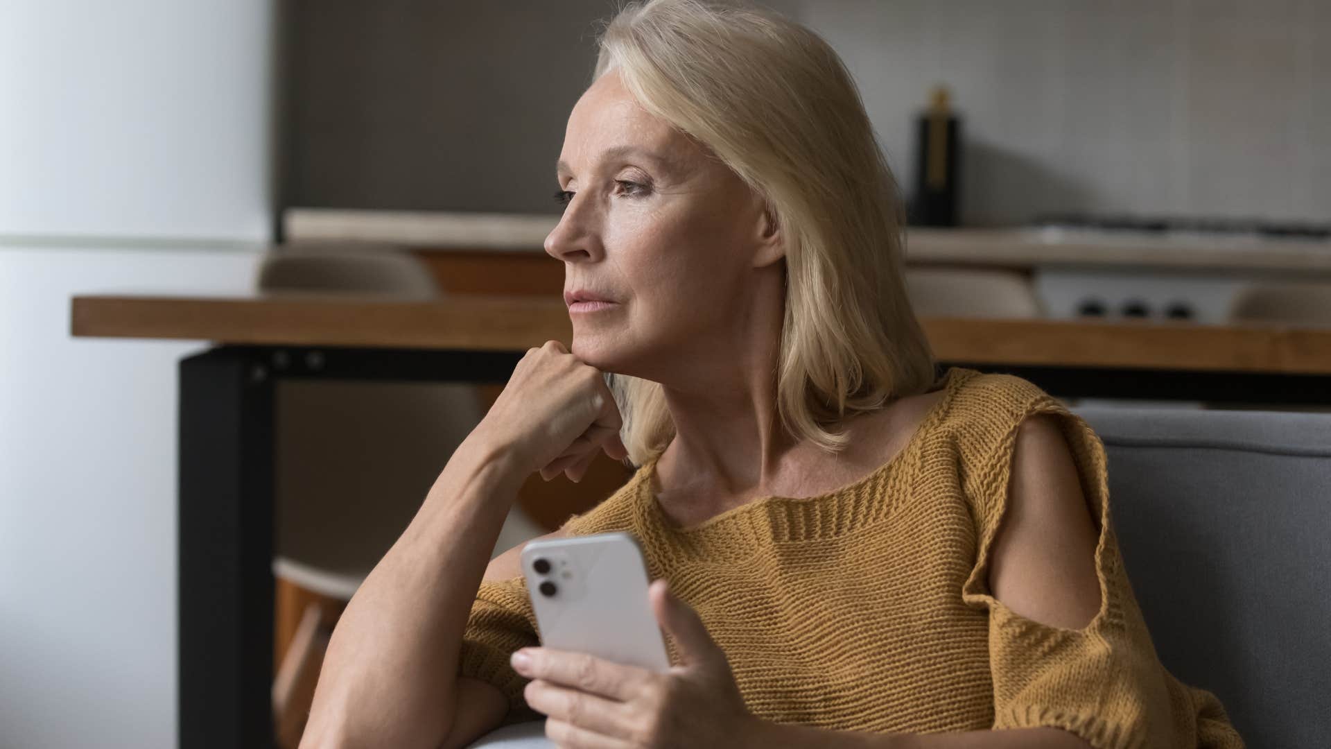 Woman holding her phone and looking serious.