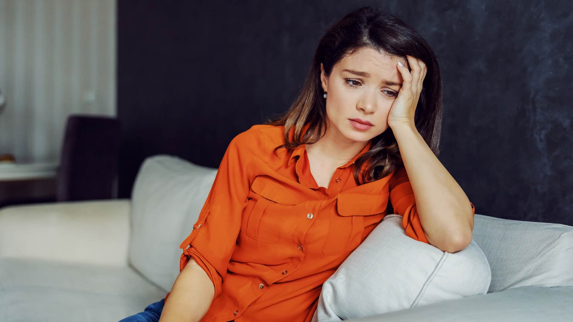 Woman looking stressed sitting on her couch.