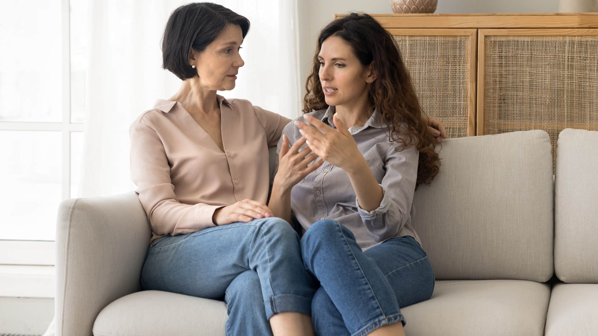 Adult woman talking to her mother on the couch. 