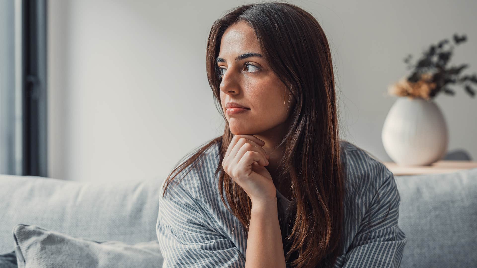 Woman looking upset staring out a window.