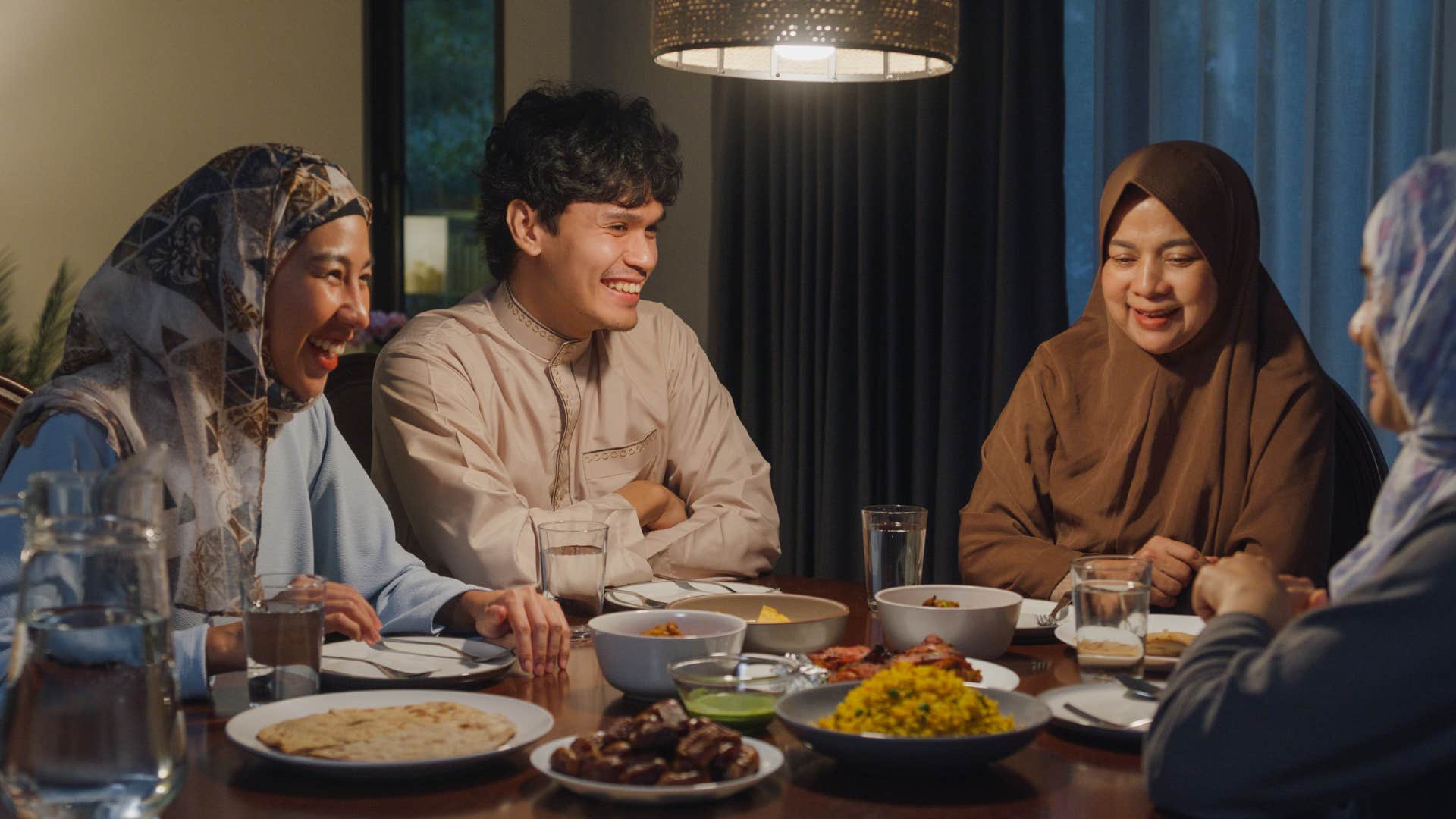 Family smiling and having dinner at a table together.